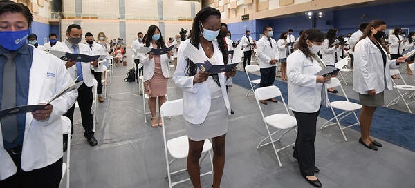 Students reading at white coat ceremony