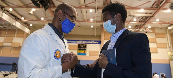 faculty and student shaking hands